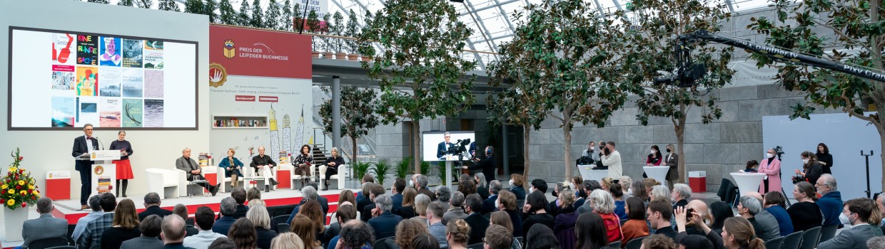 Preisverleihung vom Preis der Leipziger Buchmesse 2022 mit Publikum und Jury auf der Bühne in der Glashalle der Leipziger Messe